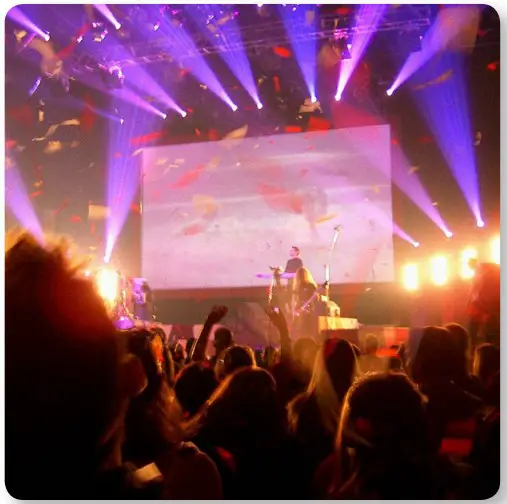 a group of people watching a band on stage in front of a crowd
