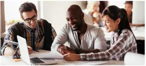 a group of people sitting at a table using a laptop